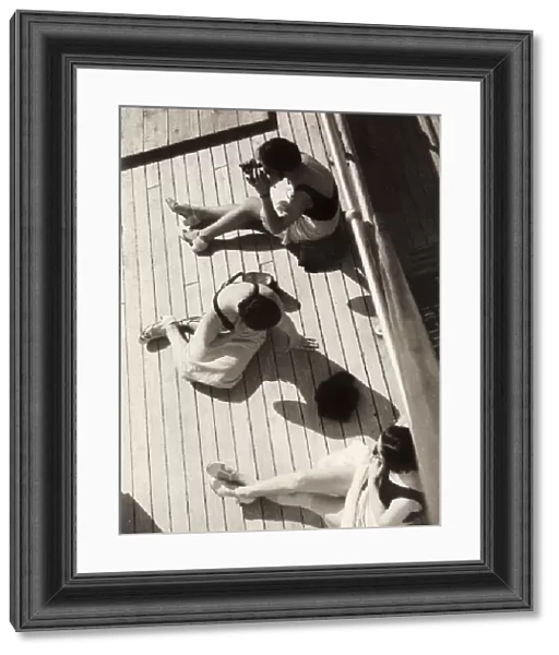 Three women sunbathing on the deck of a ship