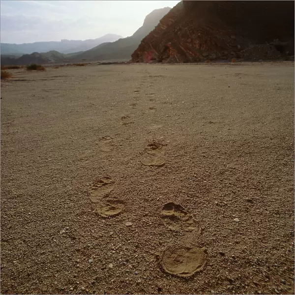 Sinai: human footprints on the sand at the layer of the Rocky Mountains of Sinai