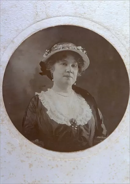 Half-length portrait of a lady in day dress and a hat decorated with small flowers. She is wearing pearl earrings, necklace and brooch