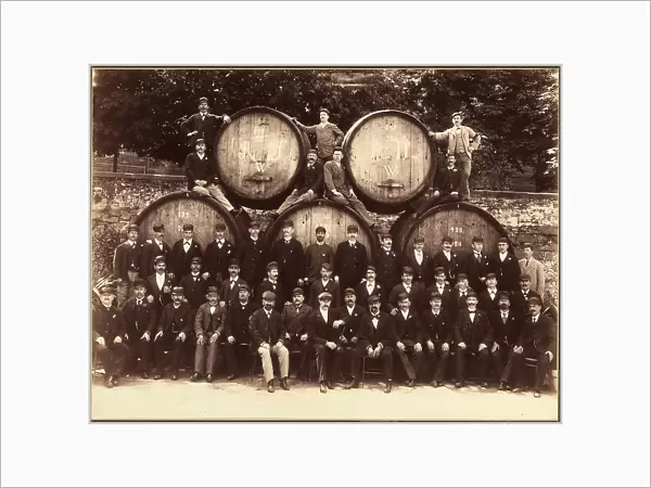 Group photo of beer makers with a few large barrels