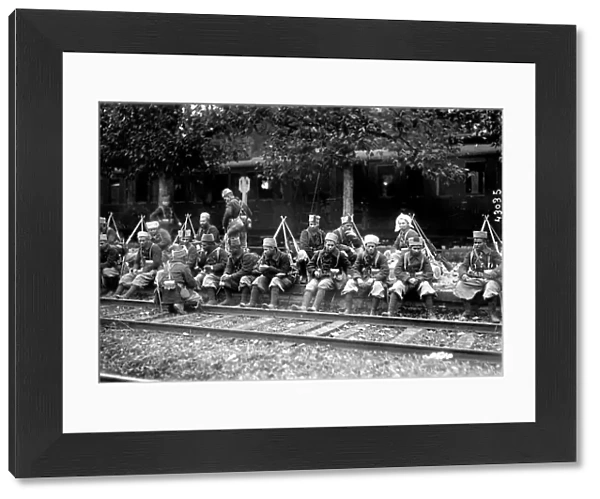 A group of native riflemen are sitting along the rail tracks, while waiting for the front