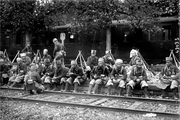 A group of native riflemen are sitting along the rail tracks, while waiting for the front