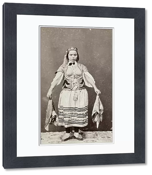 The image shows a typical Tunisian dancer. The young lady wears a traditional dress, formed by a striped skirt, an embroidered waistcoat and by a soft-leather head gear; in her hands, she holds two handkerchiefs