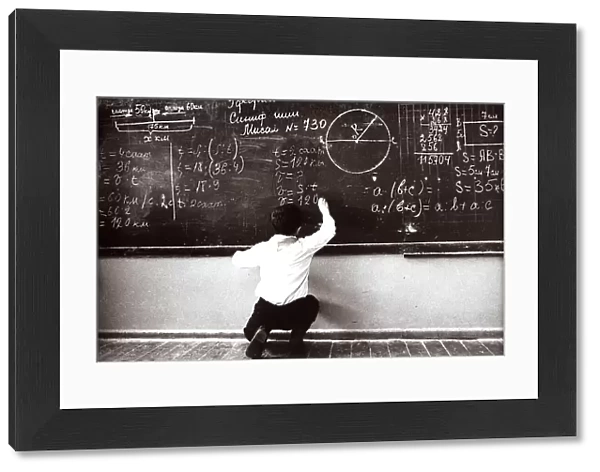 Russian boy does mathematic exercises at the blackboard