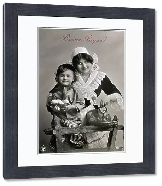 An Easter greeting card. A young woman is shown dressed as a peasant with a child. The child is holding a small basket full of eggs while the woman is holding a basket with a small rabbit crouching inside