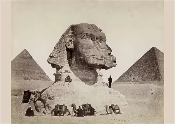 The Sphynx of Chefren with the Pyramids of Chefren and Cheops at its sides. Three men on camels are stopped in front of the monument