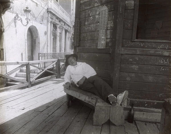 Man sleeping on a bench in a side street, Venice, Italy
