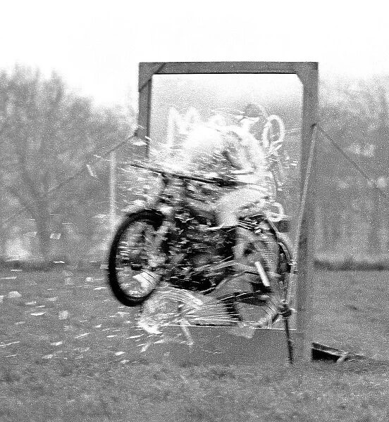 Stunt woman rides her motorbike through a glass plate, shattering it as she speeds through. Date: circa 1970s