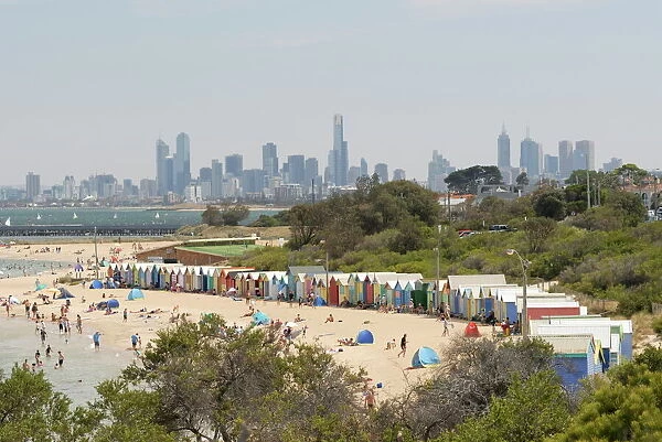 Beach scene with beach huts at Brighton Beach, Brighton, and in background skyscrapers of the city of Melbourne, Victoria