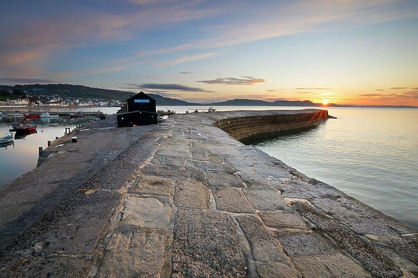 The Cobb with the cliffs of Jurassic Coast at sunrise, Lyme Regis, Dorset, England