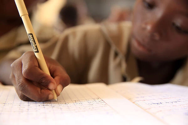 Pupil taking notes in French class in African primary school, Lome, Togo, West Africa