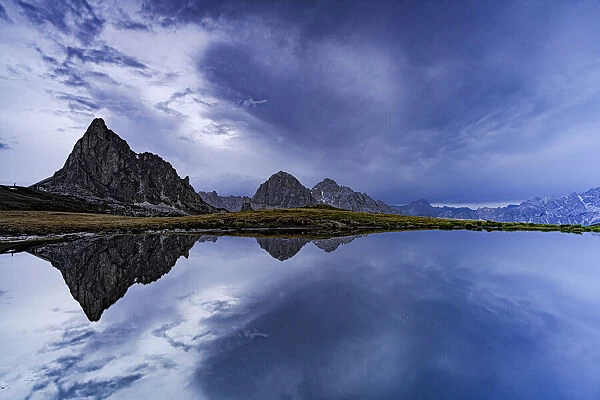 Ra Gusela and Tofane mountain peaks reflected in water under the cloudy sky at dusk, Giau Pass, Dolomites, Veneto, Italy, Europe