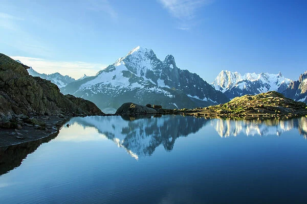 The snowy peaks of Mont Blanc are reflected in the blue water of Lac Blanc at dawn
