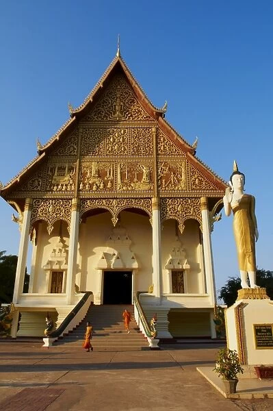 Statue of standing Buddha and monks, Pha That Luang temple, Vientiane, Laos