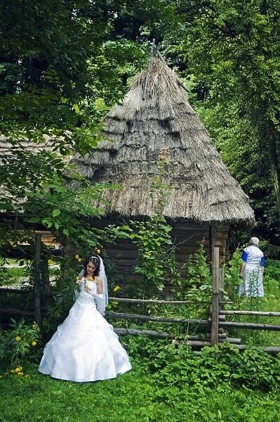 Bride stood in front of a traditional thatched roof