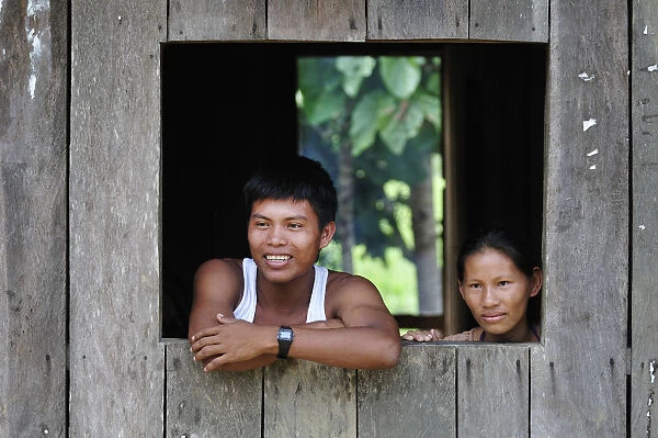 Couple looking out of window in the Amacayon Indian Village, Amazon river, Puerto Narino