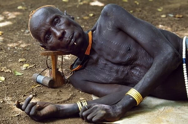 An elder of the Karo tribe rests with his head on his