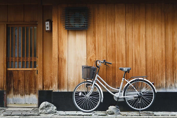 Japan, Chubu Region, Kyoto, Gion. A bicycle rests against the wall of a traditional