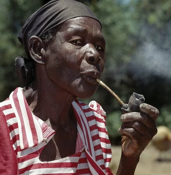 An old Luo lady smoking a traditional clay pipe