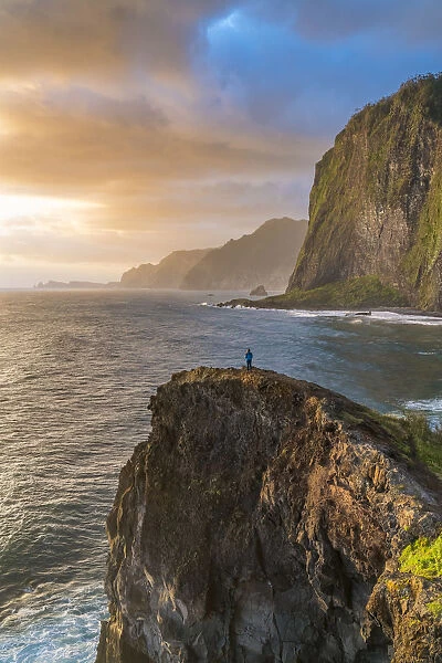 Person on a cliff watching the sunrise. Faial, Santana municipality, Madeira Island