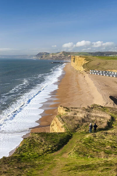 Two walkers enjoy the view along the beautiful vista from the cliffs of Burton Bradstock