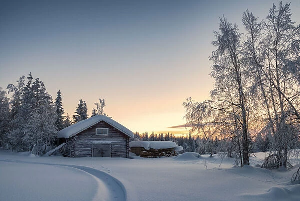 Wooden house in the snowy forest during sunset, Kiruna, Norrbotten County, Lapland