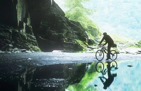A man mountain biking, in Rydal Cave, Lake district, UK