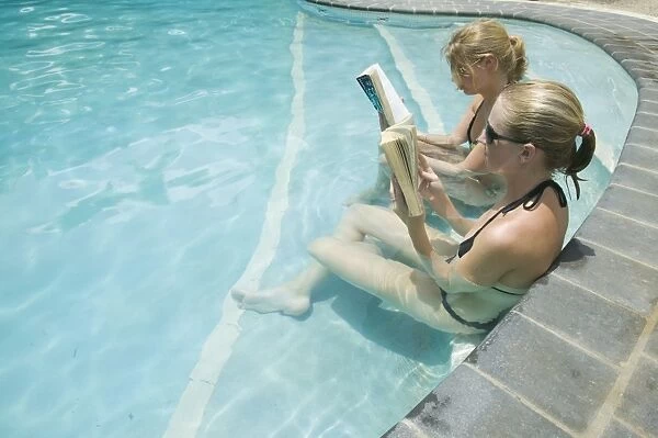 Women reading books in a swimming pool at the Walu Beach Resort on Malolo Island off Fiji