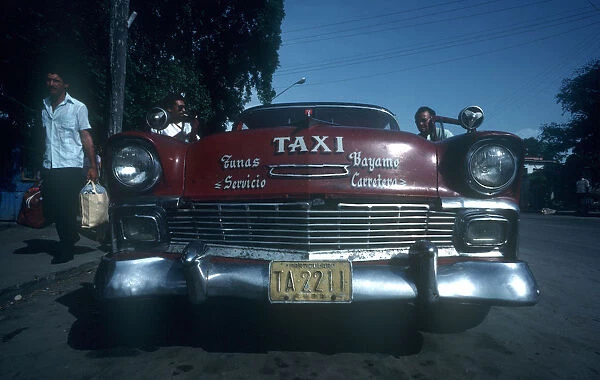 20024477. CUBA Granma Province Bayamo Red 1950s Cadillac taxi parked by the kerb