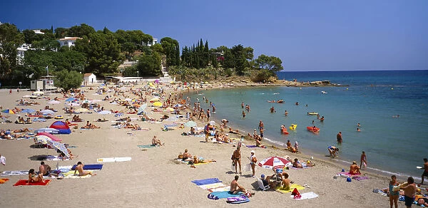 20027604. SPAIN Catalonia Llanca Curved sandy beach with people sunbathing and in the sea