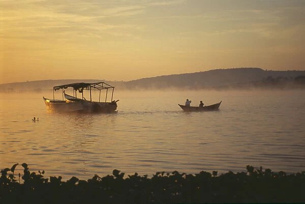20069785. UGANDA Jinja Golden sunrise over Lake Victoria. Boats silhouetted in foreground