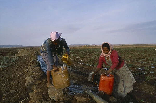 20074713. ERITREA Seraye Province Women collecting water at irrigation pipe