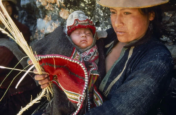 PERU Apurimac Gorge Woman carrying baby while weaving or trensing ichu grass used in