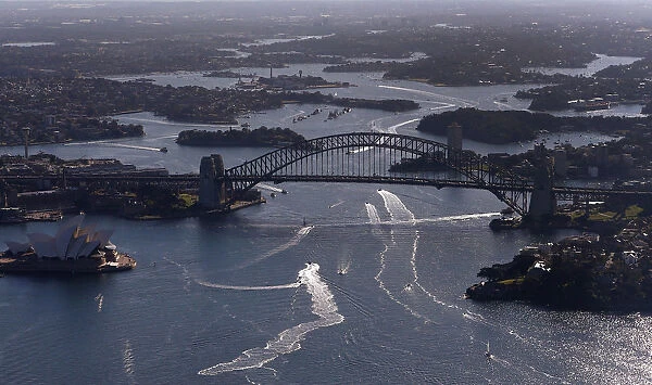 Boats navigate next to the Sydney Opera House and the Harbour Bridge on a sunny winter
