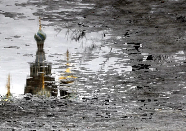The Church of the Savior on Spilled Blood is reflected in melting ice on Arts Square in