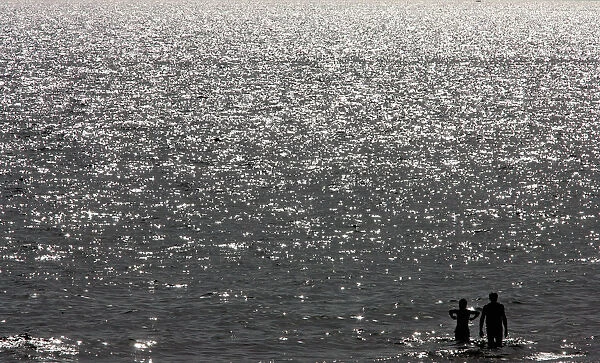 A couple is silhouetted as seeking relief from soaring temperatures at the beach in Ostia