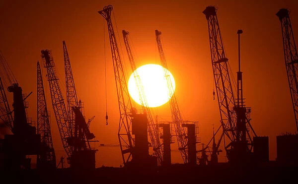 Cranes of German shipyard Blohm&Voss are silhouetted during sunset in Hamburg