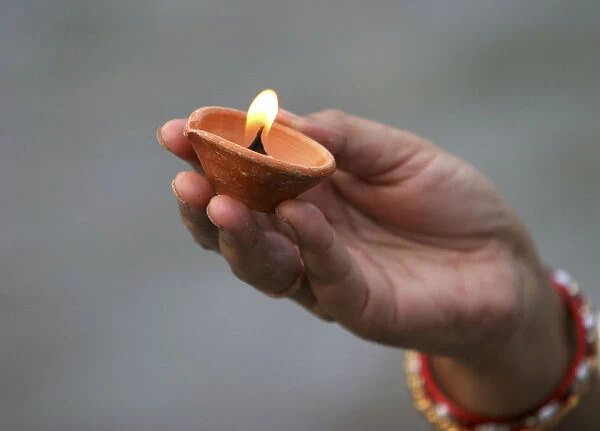 A Hindu devotee holds an earthen lamp as she offers prayers to the Sun god in Siliguri