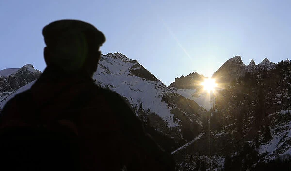 A man watches the sun shining through Martins Hole, a natural gap just underneath the