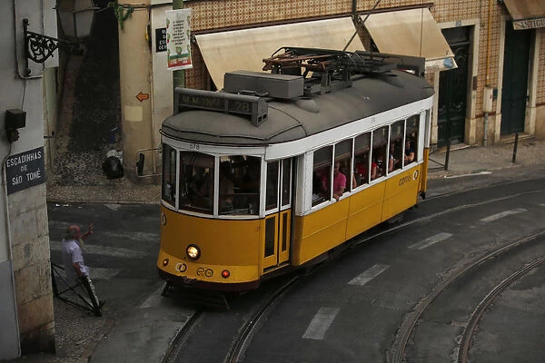 A man waves to the driver of a tram at Alfama neighborhood in Lisbon