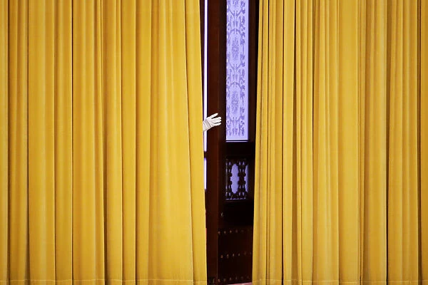 A member of staff appears from behind curtains before the visit of British Prime Minister