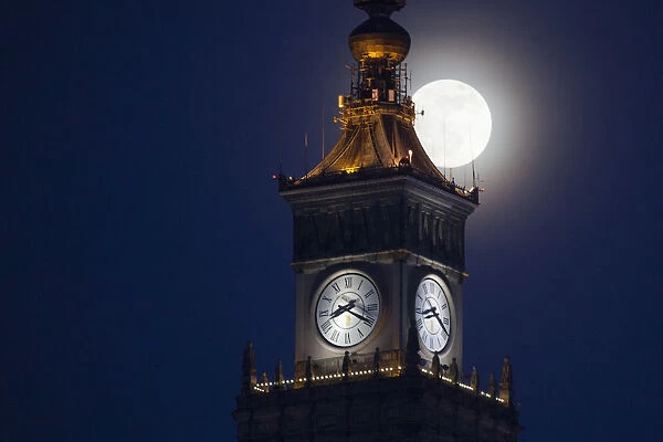 The moon is seen above the Palace of Culture and Science in the center of Warsaw