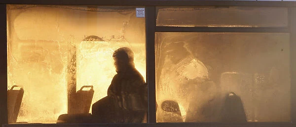 Passenger is seen silhouetted through a frosted bus window