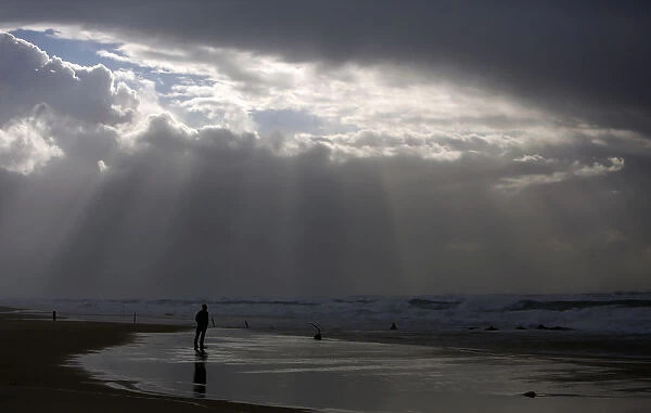 A person stands on the shores of the Mediterranean Sea on a stormy day at Nitzanim beach