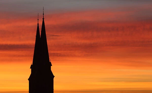 Spires of Familienkirche are silhouetted against sky during sunrise in Vienna