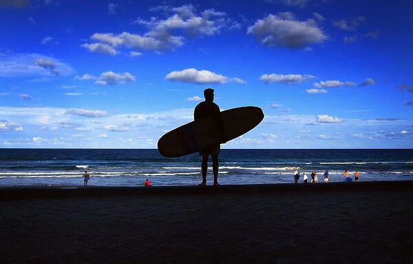 A surfer holds his board as he looks over Manly Beach in Sydney