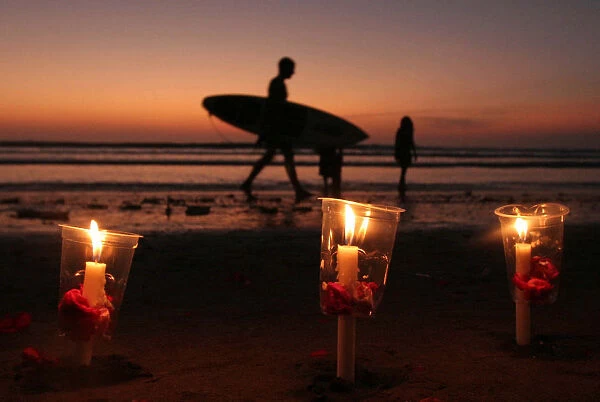 A surfer walks past candles during a commemoration of the 2002 Bali bombing in Kuta