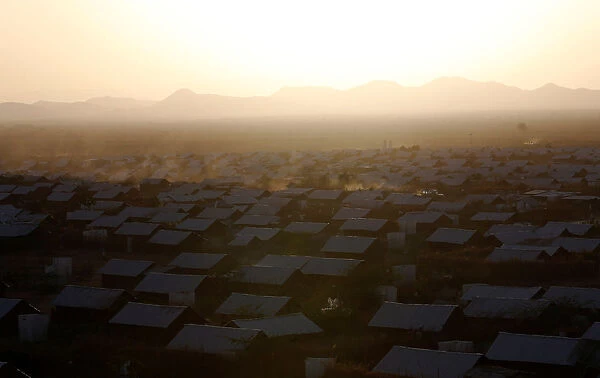 A vehicle drives at dusk within recently constructed houses at the Kakuma refugee camp in