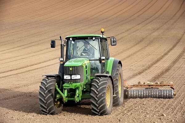 John Deere tractor pulling soil press, rolling seedbed in arable field, Kelso, Scottish Borders, Scotland, september
