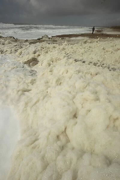 Sea foam washing up on beach after storm, Hengistbury Head, Dorset, England, april